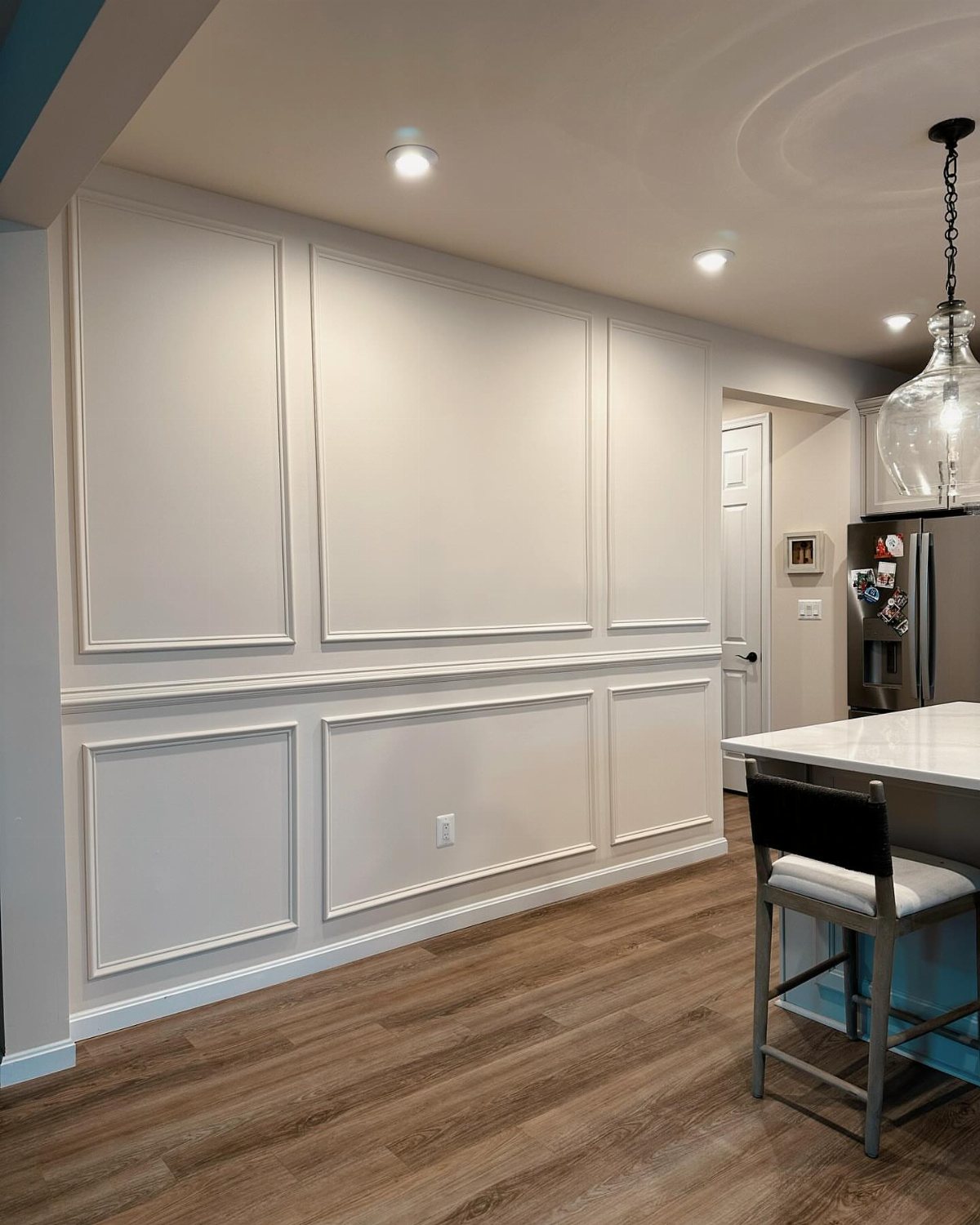 Monochromatic light gray wall with decorative panel molding and a matching chair rail.