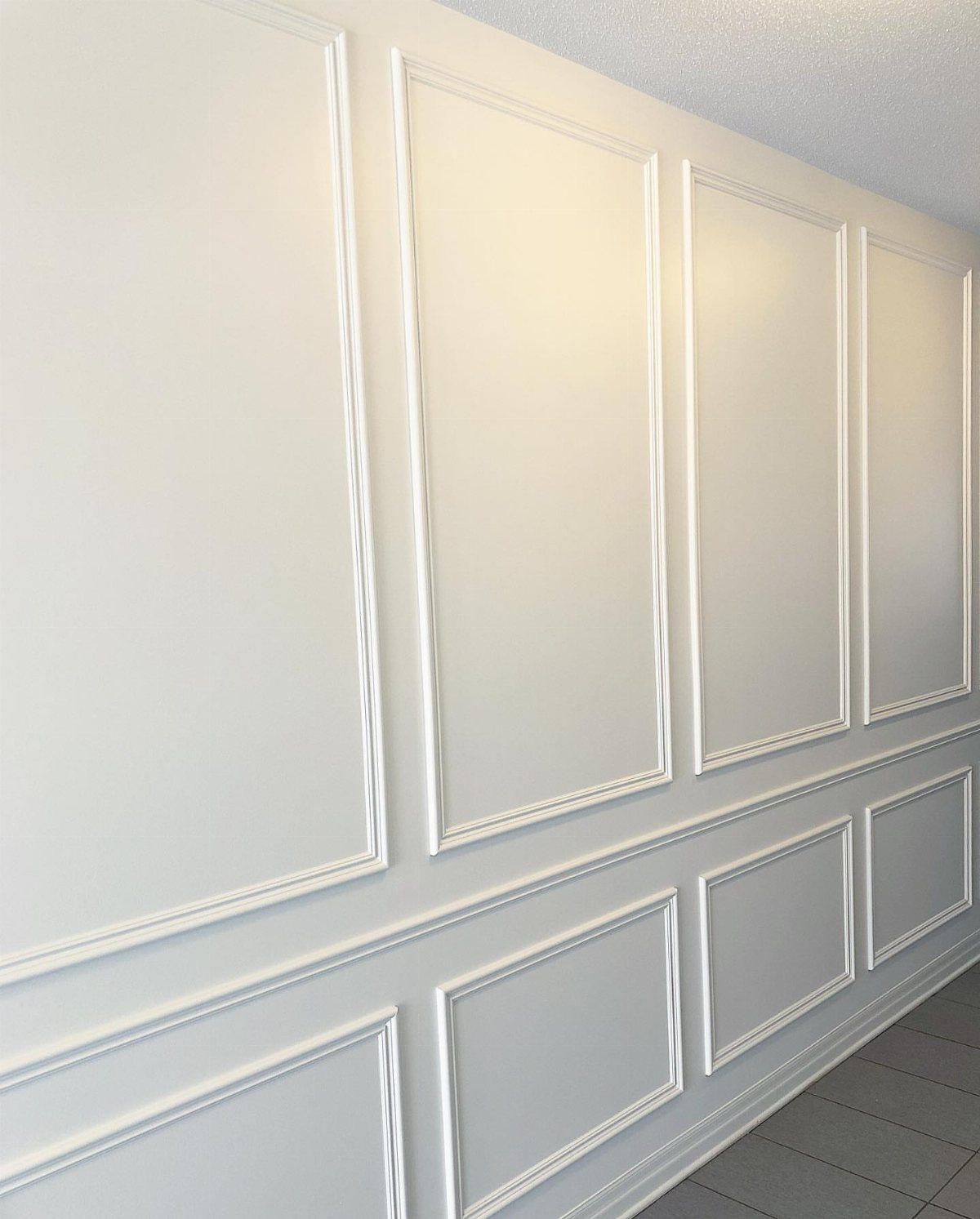 White wainscoting wall panels with a horizontal chair rail trim piece installed.