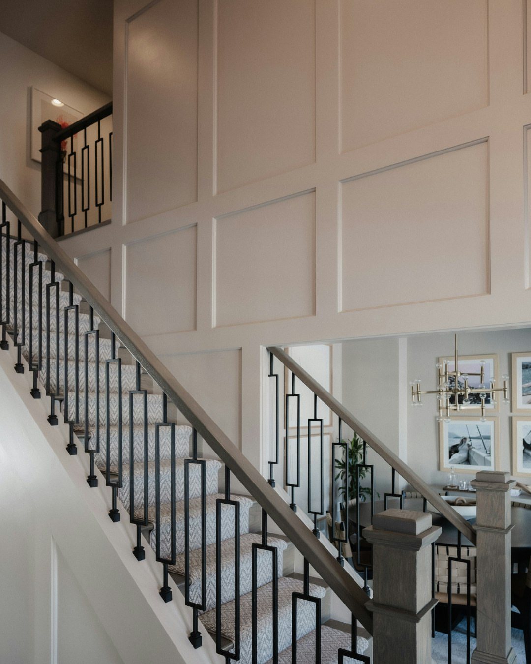 Staircase with black railings next to large rectangular floor to ceiling wall paneling.