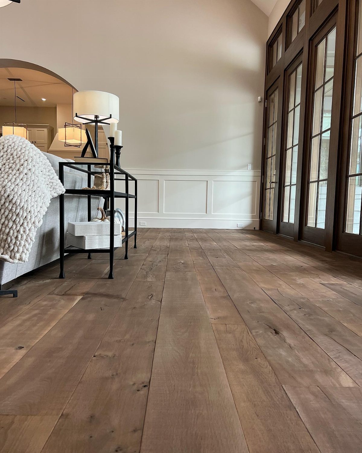Wide rustic hardwood planks with natural grain patterns in a bright, modern living space.