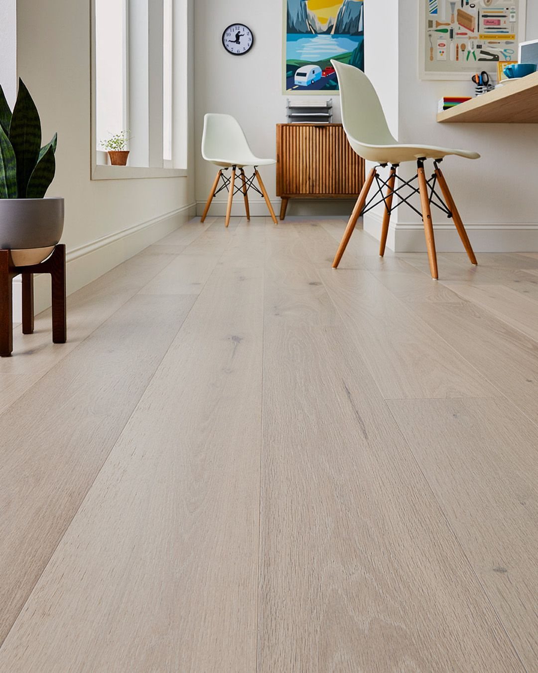 Light wood plank flooring stretching through a bright, modern room with white furniture.