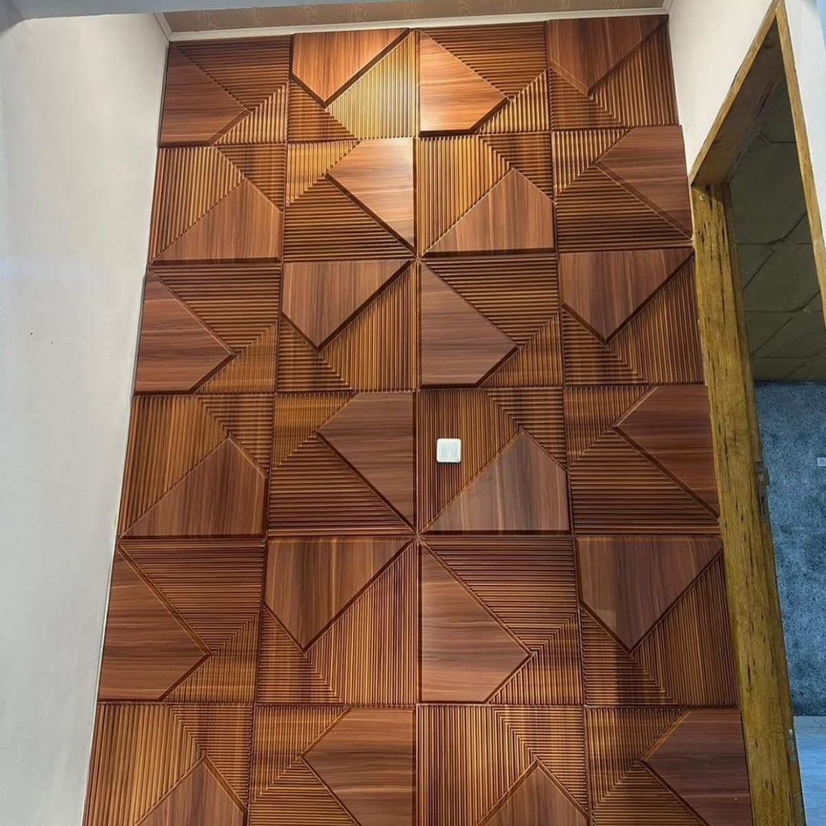 Geometric wood panels arranged in a repeating triangular pattern on a large interior wall.