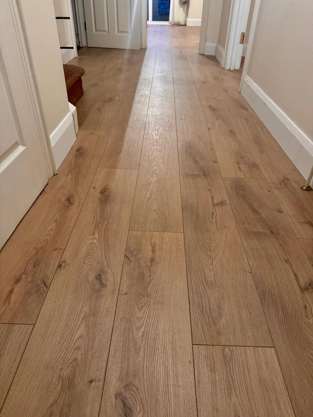 Light brown oak wood floor planks with visible grain patterns in a hallway.